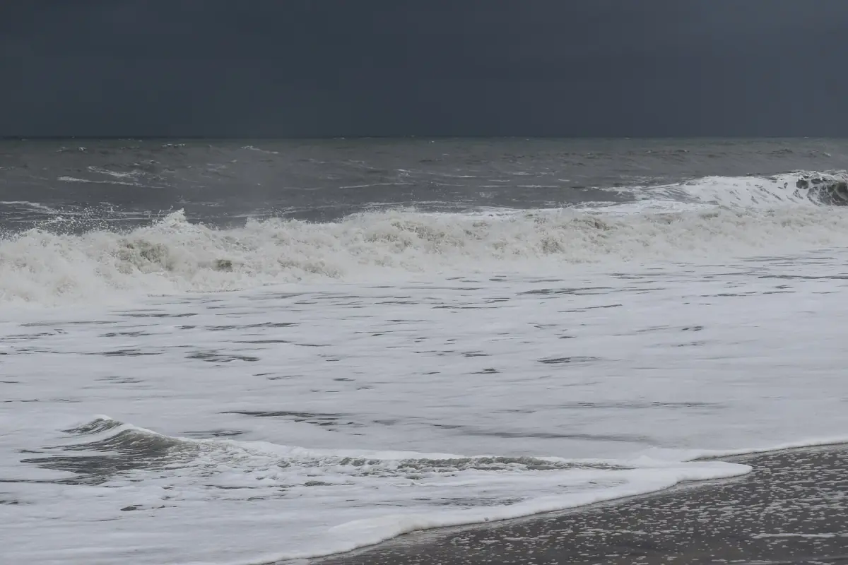 Grey monsoon sky and rough surf on the shore at Alappuzha beach