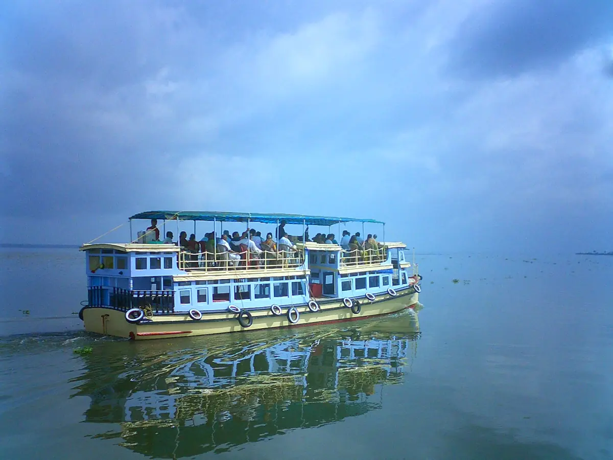 Double-deck passenger boat crossing calm open backwater near Alappuzha