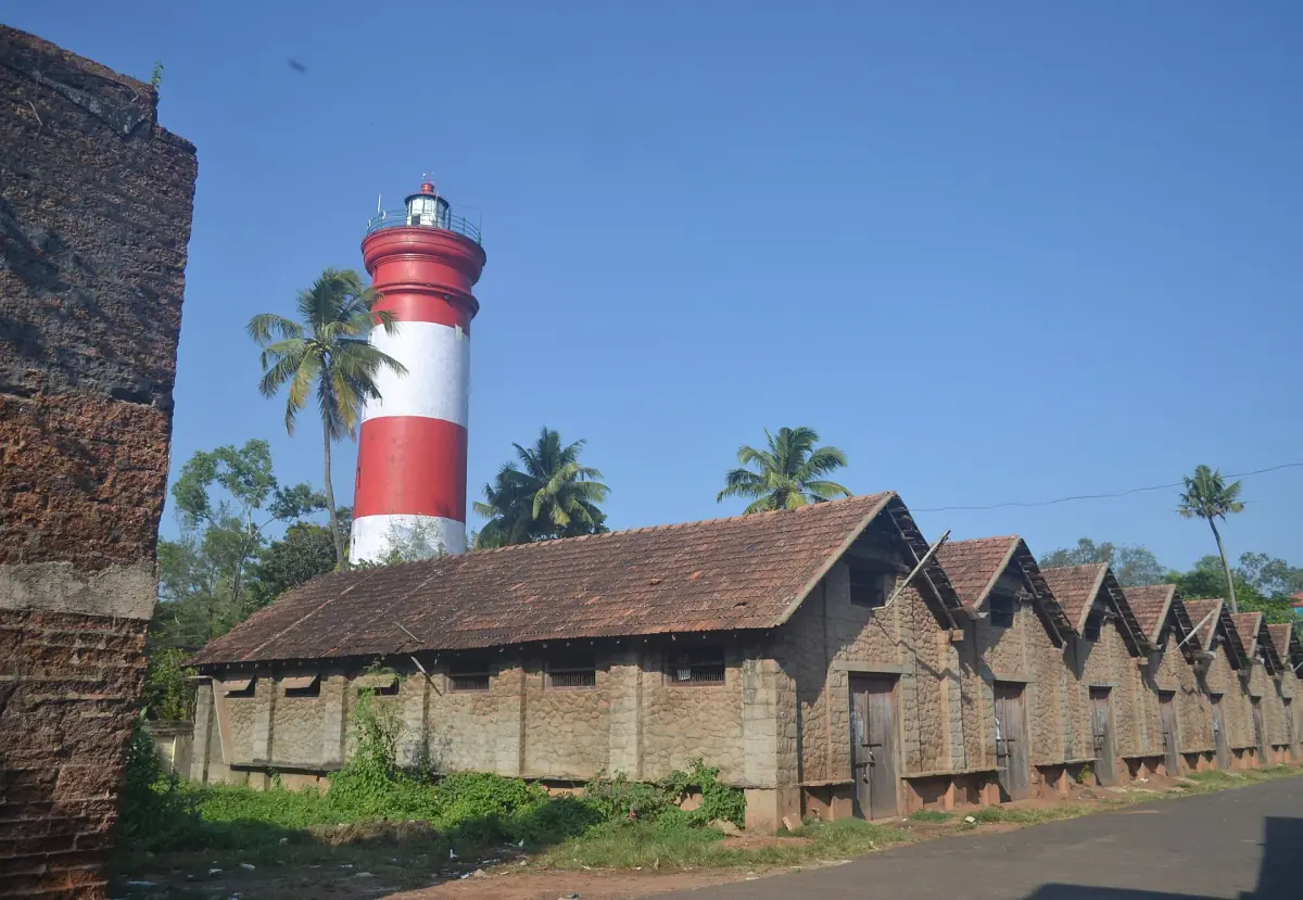 Red and white striped Alleppey lighthouse behind palms and old tiled warehouses