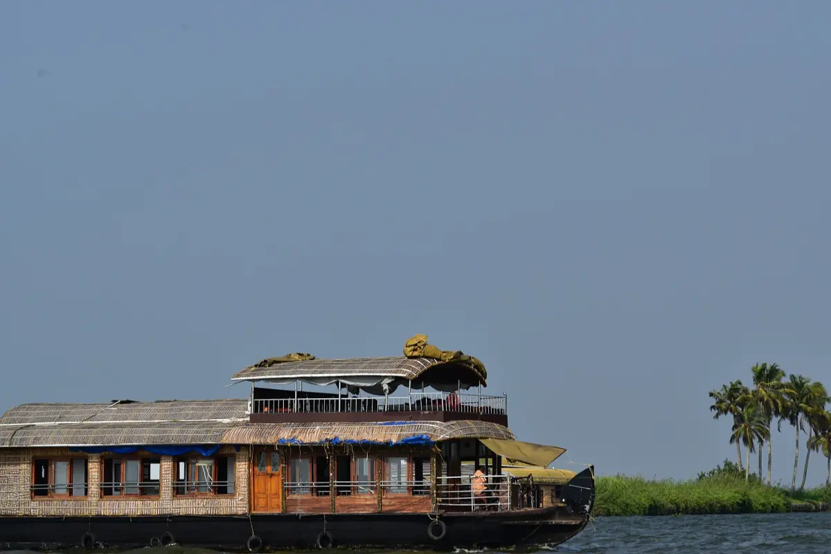 Houseboat under a dark stormy sky beside a palm-covered shore in Alappuzha