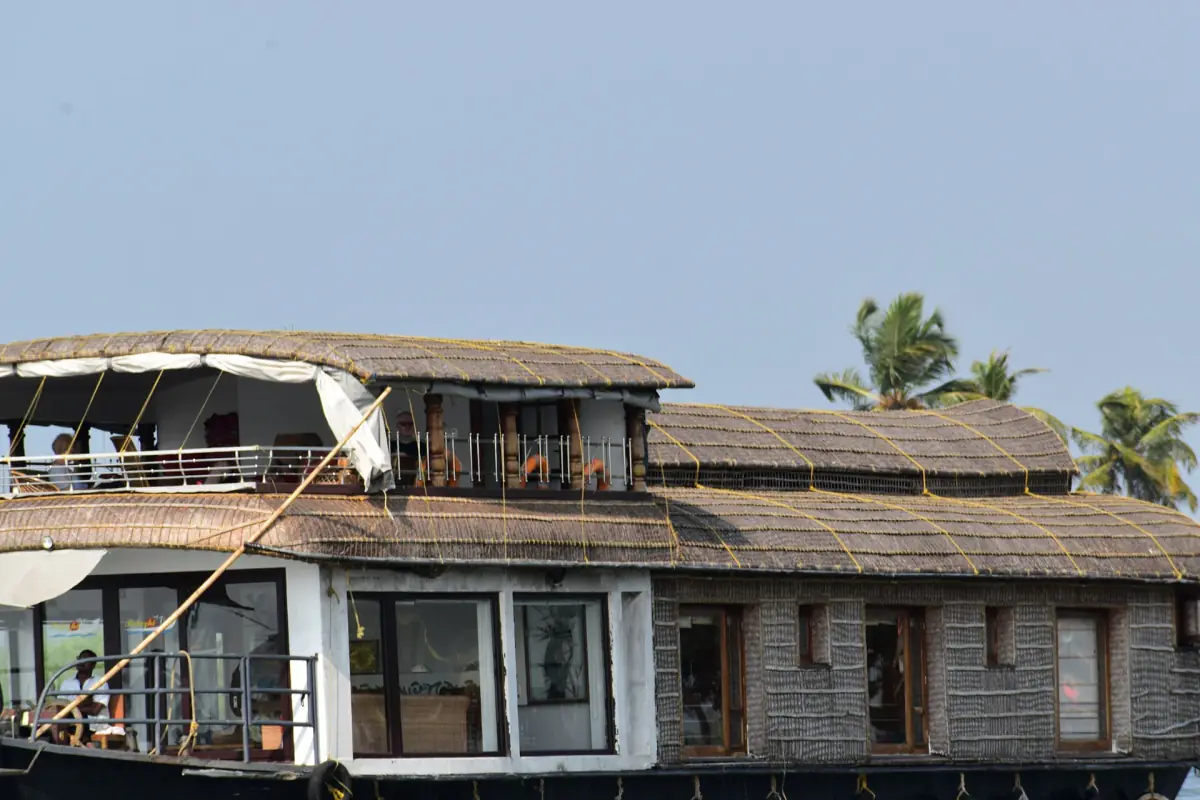 Close view of a two-deck houseboat with thatched side walls and open upper deck
