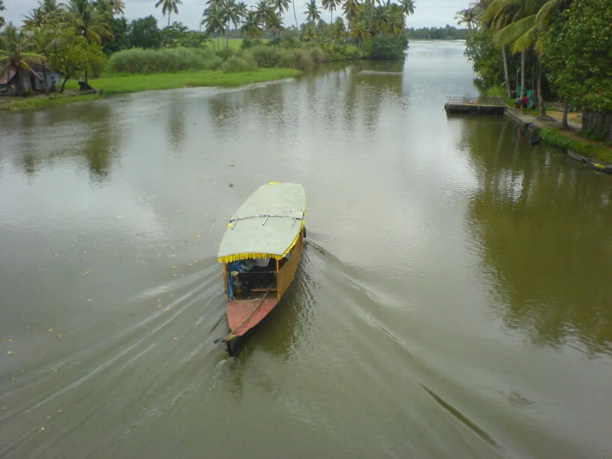 Narrow motorboat on a green backwater channel at Kumarakom in Kottayam district