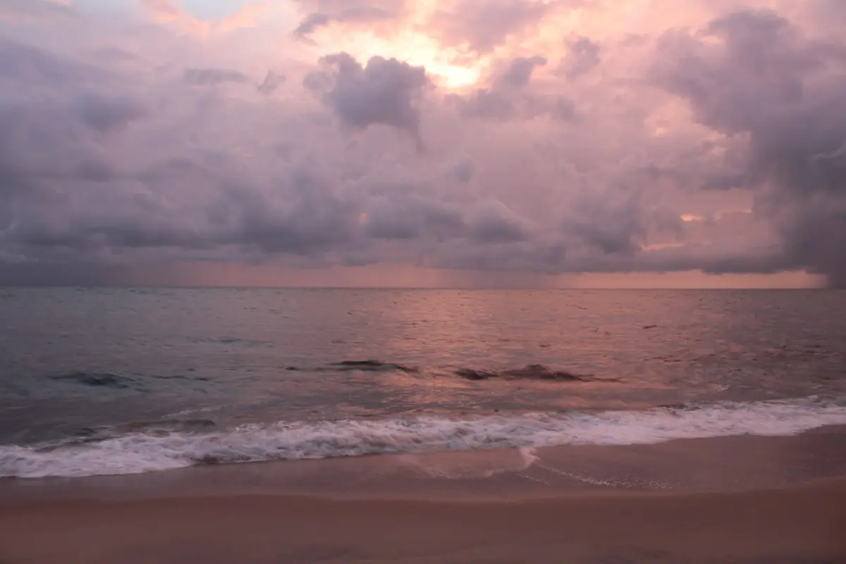 Sunset over the sea at Marari beach with purple clouds and wet sand