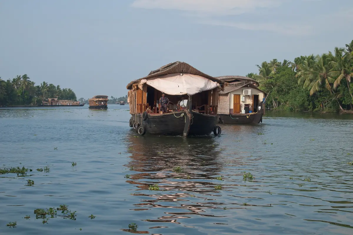 Two wooden houseboats side by side on wide calm Kerala backwater water